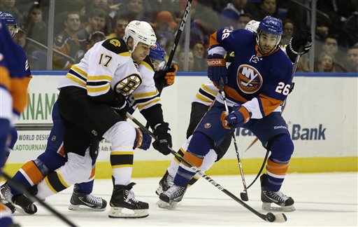 Boston Bruins left wing Milan Lucic (17) controls the puck in front of New York Islanders left wing Matt Moulson (26) in the first period of their NHL hockey game at Nassau Coliseum in Uniondale, N.Y., Tuesday, Feb. 26, 2013. (AP Photo/Kathy Willens)