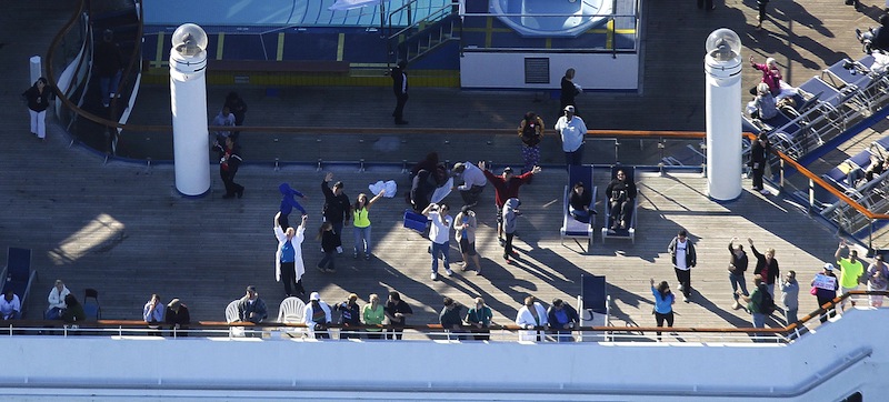 In this aerial photo, passengers congregate on an upper deck of the disabled Carnival Lines cruise ship Triumph as it is towed to harbor off Mobile Bay, Ala., Thursday, Feb. 14, 2013. The ship with more than 4,200 passengers and crew members has been idled for nearly a week in the Gulf of Mexico following an engine room fire. (AP Photo/Gerald Herbert)