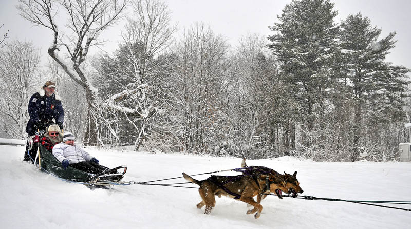 Kevin Quist, of Augusta, gives Sue, front, and Tim Stiefel, of Winthrop, a ride in a dog sled Sunday at Viles Arboretum in Augusta. The dogs are scheduled for two more pulls this year for guests at the arboretum.