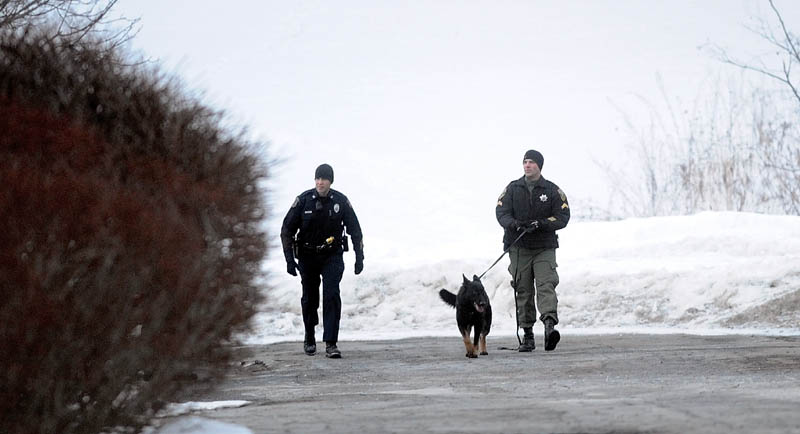 A Waterville police officer, left, and Kennebec County Sheriff K-9 unit search the closed dirt access road that connects the doctor's complex at 325 Kennedy Memorial Drive with Lincoln Street for a man who robbed Key Bank on Kennedy Memorial Drive Thursday afternoon.