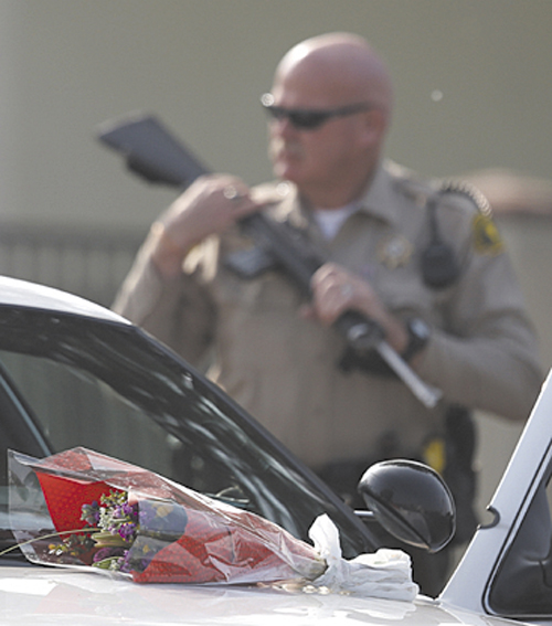 Flowers placed on a police vehicle near the area where a shooting took place in Riverside, Calif, Thursday. Thousands of police officers are searching for one of their own: a former Los Angeles officer, Christopher Dorner, who is angry over his firing and is sought in a deadly shooting rampage after warning he would wage "warfare" on those who wronged him, authorities said.
