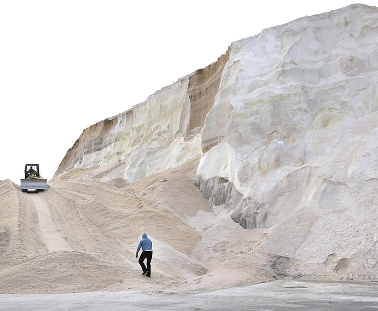 A worker walks up towards a plow smoothing a large salt pile at Eastern Salt Company in Chelsea, Mass., Thursday, in preparation for a major winter storm headed toward the U.S. Northeast. The National Weather Service calls for up to 2 feet of snow expected for a Boston-area region that has seen mostly bare ground this winter.