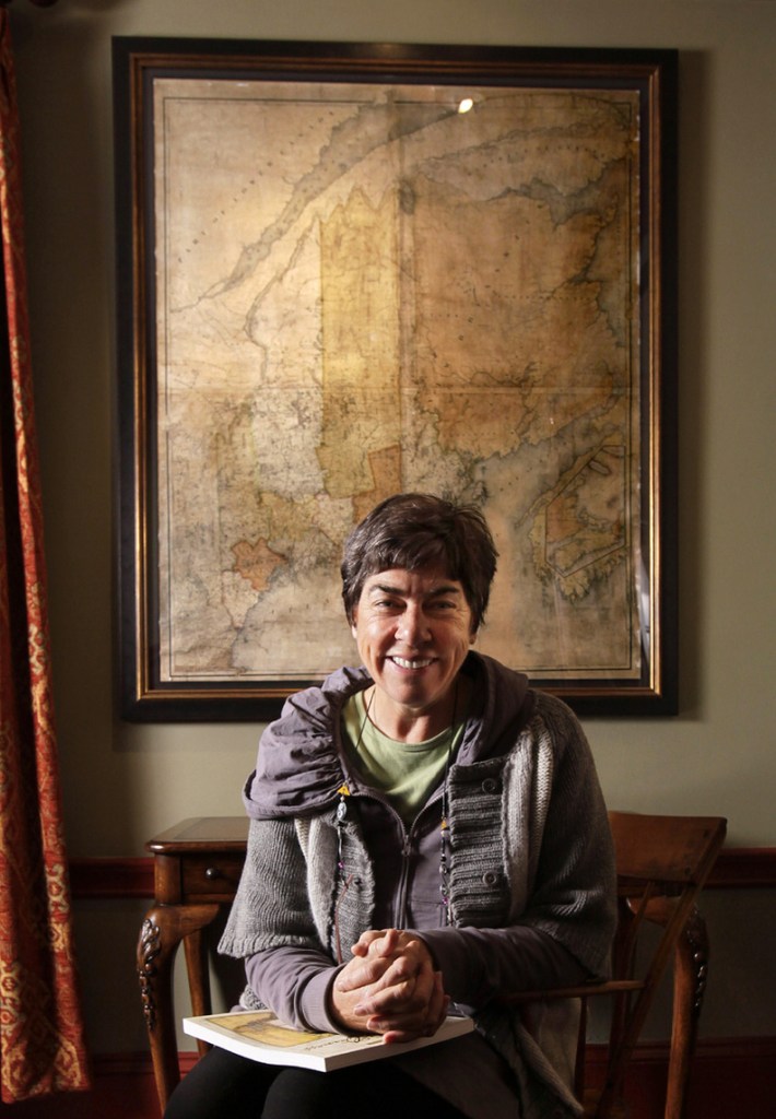 Conservationist Roxanne Quimby poses in front of a 180-year-old map of Maine at her home in Portland. Two studies commissioned by her foundation suggest communities near national parks outpace the national average for economic development.