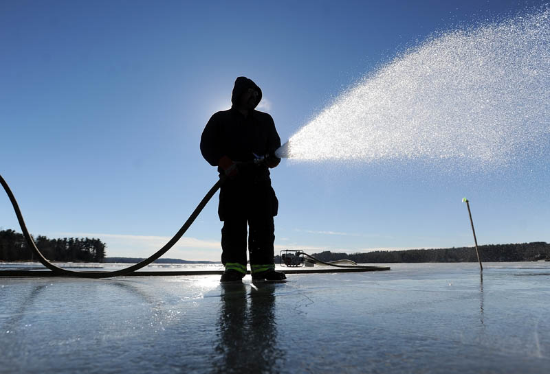 Joe Labbe, with the China Village Fire Department, sprays water on the northeast end of China Lake, off Lakeview Drive, on Thursday in preparation for Saturday's Maine Pond Hockey Classic. Volunteers are trying to get the surface ready before the impending storm settles in over the area.