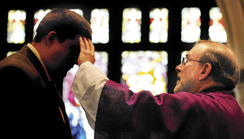 The Rev. Francis Morin places ashes on a person's forehead during an Ash Wednesday mass at St. Mary Church in Augusta.