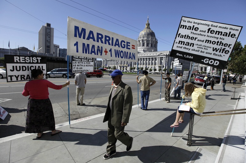 This Sept. 6, 2011 file photo shows a man walking past a group of people protesting against gay marriage outside a courtroom where the California Supreme Court was hearing arguments in San Francisco. The Obama administration on Thursday will ask the Supreme Court to overturn California's ban on gay marriage and take a skeptical view of similar bans. (AP Photo/Eric Risberg, File)