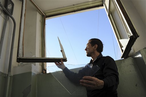 A local resident assesses damage to a window broken by a shock wave from a meteor explosion in Chelyabinsk, about 930 miles east of Moscow, on Friday.