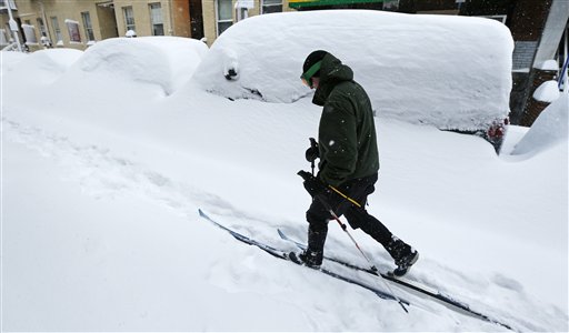 Mike Brown, of Boston, cross country skis past snow-covered cars through the Chinatown neighborhood of Boston on Feb. 9. Scientists point to both scant recent snowfall in parts of the country and this month's whopper of a Northeast blizzard as potential signs of global warming. It may seem like a contradiction, but the explanation lies in atmospheric physics.