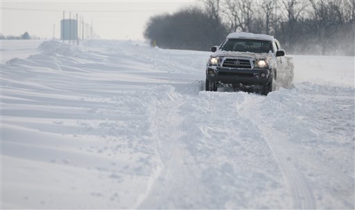 A truck makes its way along a snow covered road in Sedgwick County, Kan., on Tuesday. The storm dropped a half-foot or more of snow across Missouri and Kansas and cut power to thousands. Gusting winds blew drifts more than 2 feet high and created treacherous driving conditions for those who dared the morning commute.