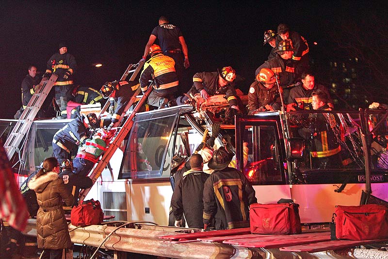 Emergency personnel remove passengers at the scene of a bus crash Saturday in Boston. Authorities say a charter bus heading from Harvard University to Pennsylvania struck a bridge in Boston, injuring 33 people.