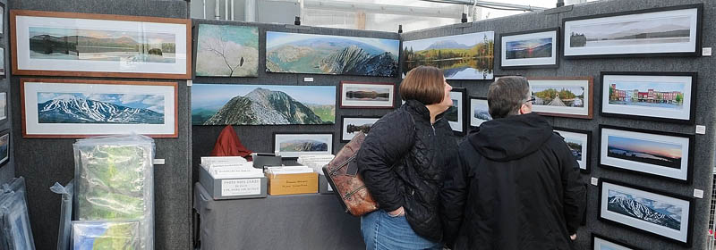 Sherry Levesque, left, and Dale Haywood, both of Winthrop, look at panoramic photos by Farmington artist Scott Perry during the Cabin Fever art show at Longfellow's Greenhouses on Saturday, in Manchester.
