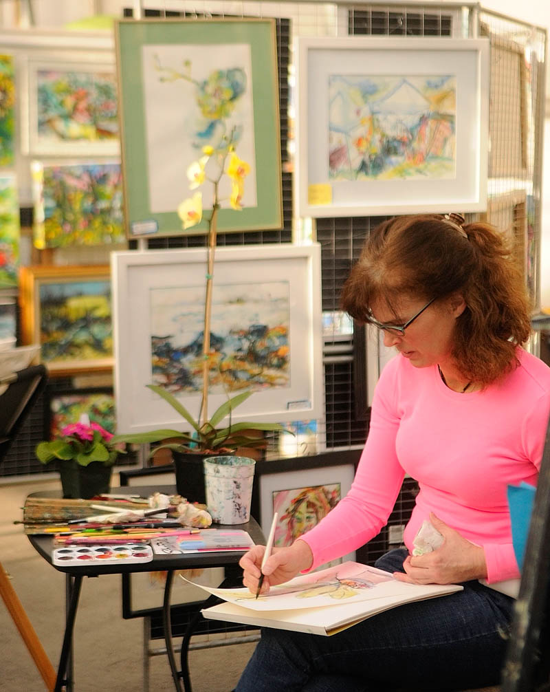 Artist Laurie Proctor-Lefebvre works in her booth while waiting for customers during the Cabin Fever art show at Longfellow's Greenhouses on Saturday, in Manchester.