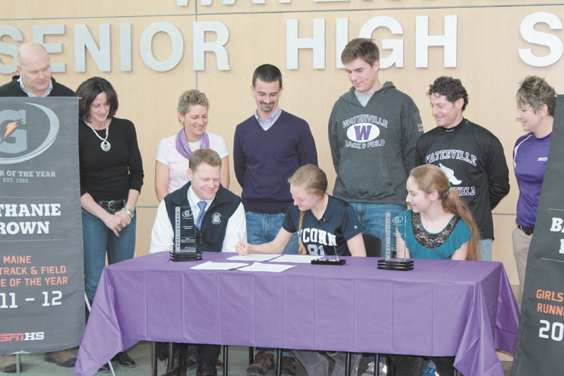 MAKING IT OFFICIAL: Waterville enior Bethanie Brown, center, signs a National Letter of Intent to compete on University of Connecticut cross country and track and field teams, Friday at Waterville Senior High School. Brown is joined at the signing by her father Ted, front left, her sister Lauren, front right, as well (back row, left to right) former Waterville athletic director Doug Frame and his wife Angela, track coaches Michelle Fowler, Rob Stanton, Matt Gilley, Ian Wilson, and Waterville athletic director Heid Bernier.