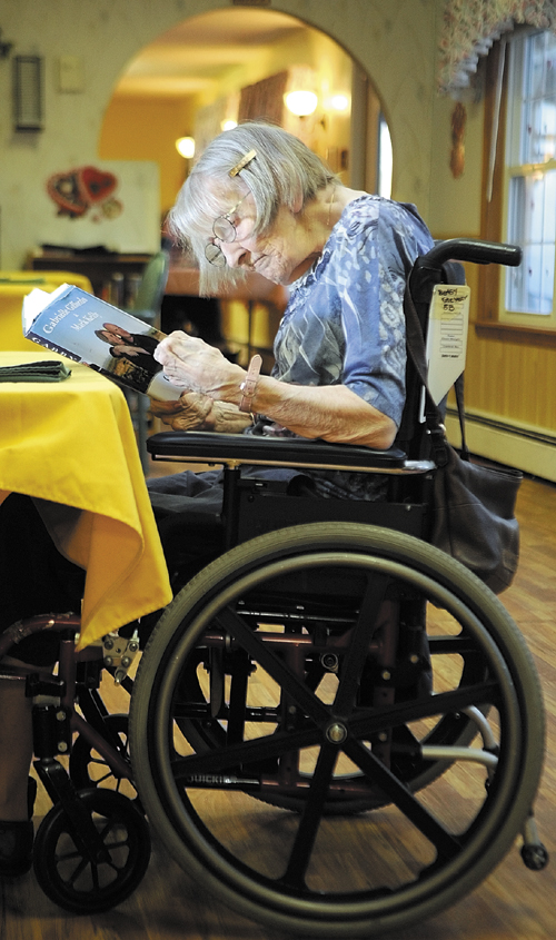 Betsy Stevens reads a book in the dining room on Friday at Heritage Rehabilitation & Nursing Center in Winthrop.