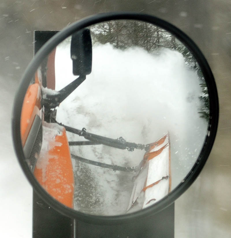 A reflection in mirror snow flying of the wing plow, on the side of the truck driven by Augusta Public Works plow truck driver Stan Moore, on Saturday.