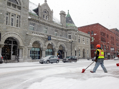 McGee construction employee Mike Abbott clears snow on Water Street in Augusta on Friday.