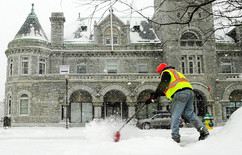 McGee Construction employee Mike Abbott shovels snow this morning on Water Street in front of the Olde Federal Building in Augusta.