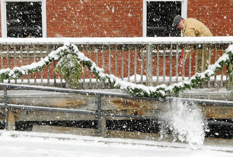 Jason McFarland shovels snow off the deck of Gagliano's restaurant around 11:15 a.m. on Friday, during the winter storm in downtown Augusta.