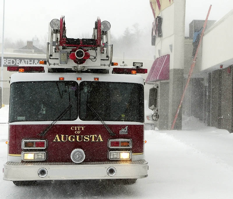 Augusta's ladder truck sits in front of Turnpike Mall, off Whitten Road in Augusta, as an Augusta Fuel Co. technician climbs onto the roof to check the heating system, around 3:20 p.m. on Saturday. The fire department responded to call about high carbon monoxide levels in the building.
