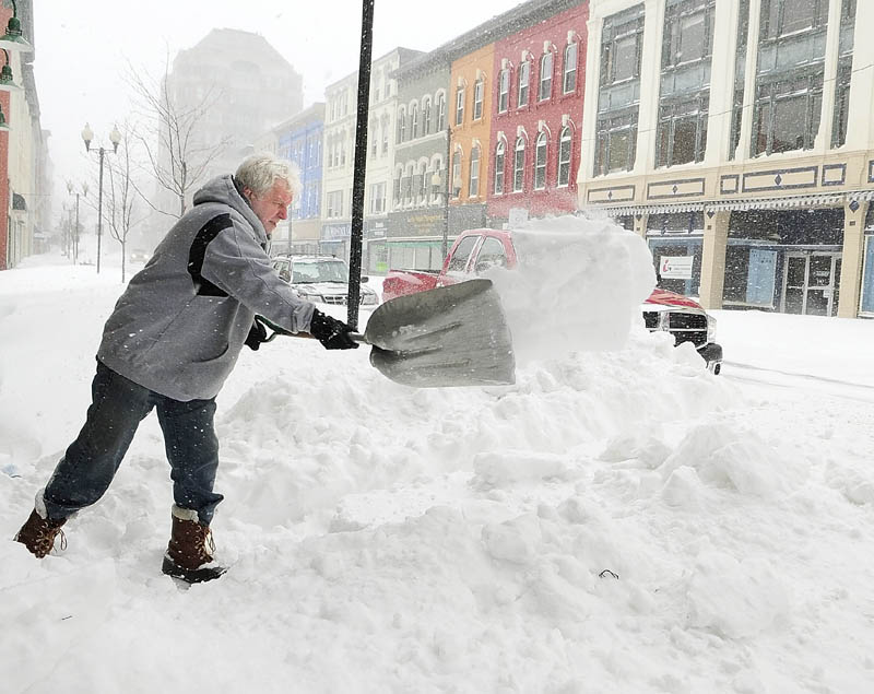 Brad Shaw shovels a path to the door of his Fussbudget's Sports Card shop around 12:25 p.m. on Saturday.