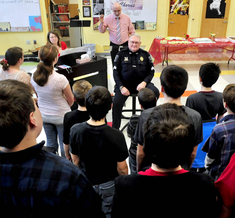 School Resource Officer Dusty Woodside, seated, was surprised by 75 seventh and eighth grade students at Messalonskee Middle School in Oakland who sang Valentine's Day songs in honor of his many years involved in schools. Woodside is retiring this summer. Behind Woodside are co-Chorus Directors Pamela and Kevin Rhein.