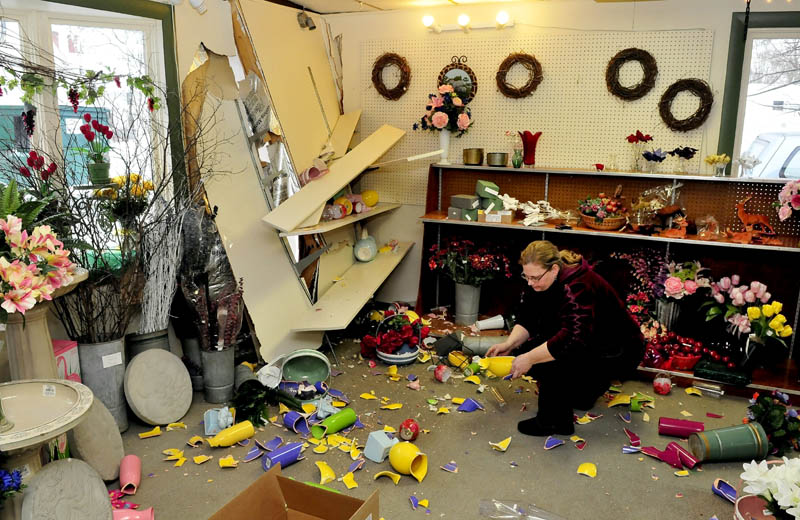 Boynton's Greenhouse Manager Ellen Withee picks up inventory that was knocked down after a truck slammed and punctured a wall at the Skowhegan business on Wednesday evening. Withee said she believes there may be $5,000 worth of damage.