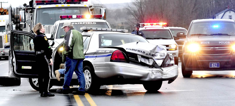 Fairfield police officer Shana Blodgett and Detective Sgt. Kingston Paul confer outside the cruiser that was destroyed, injuring officer Bill Beaulieu, after the cruiser and a truck collided on U.S. Route 201 in Fairfield on Thursday.