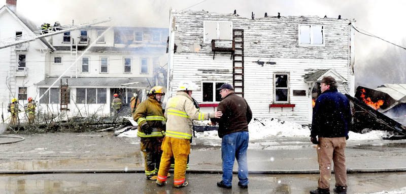Unity Fire Chief Dennis Turner puts a hand on building owner Ralph Nason Sr. as fire consumes his seven-apartment building on Main Street in Unity on Saturday. At right is Ralph Nason Jr., who said the fire may have started near a boiler and the building is insured. There were no reported injuries.
