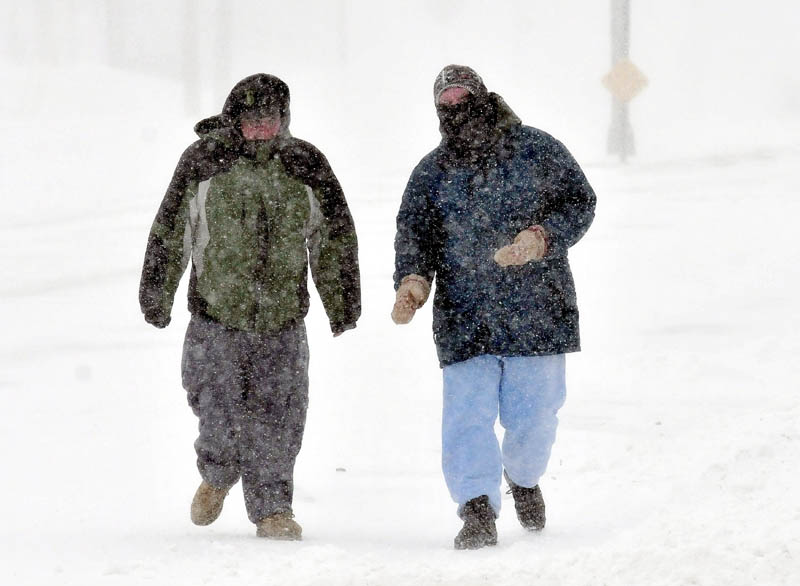 Nick Hunt, left, and Patrick Malloy walk into wind-blown snow in Waterville during blizzard-like conditions on Saturday. Both men said the weather was both cold and terrible.