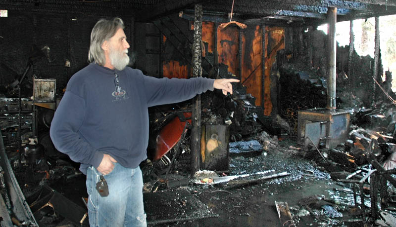 Ron Pelletier, of St. Albans, points to the shell of a Harley Davidson motorcycle destroyed in a garage fire Wednesday morning at his home on Webb Ridge Road. Pelletier said he lost $100,000 in tools and equipment.