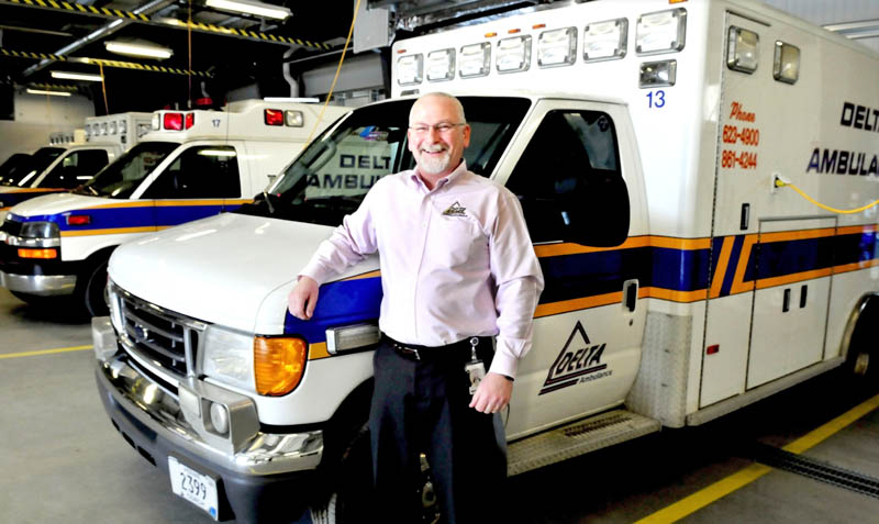 Delta Ambulance Director Tim Beals beside ambulances at the new Waterville headquarters. The company has earned the 2012 Business of the Year award from the Mid-Maine Chamber of Commerce.