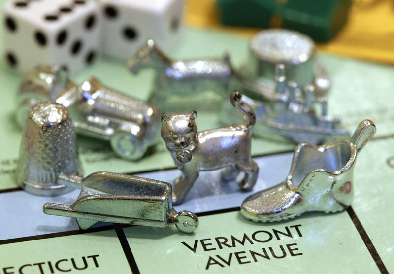 The newest Monopoly token, a cat, center, rests on a Boardwalk deed next to other tokens still in use including the wheelbarrow, left, and the shoe, right, at Hasbro Inc. headquarters, in Pawtucket, R.I.. Voting on Facebook determined that the cat would replace the iron token.