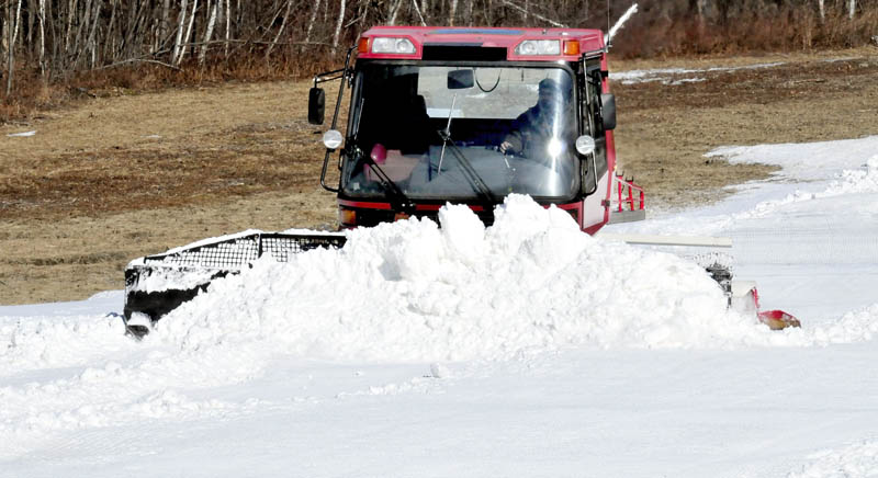 Sam Green of the Waterville Parks and Recreation department uses a snow groomer to move piles of snow made at night by snow-making machines at the Quarry Road Recreation Area on Tuesday.