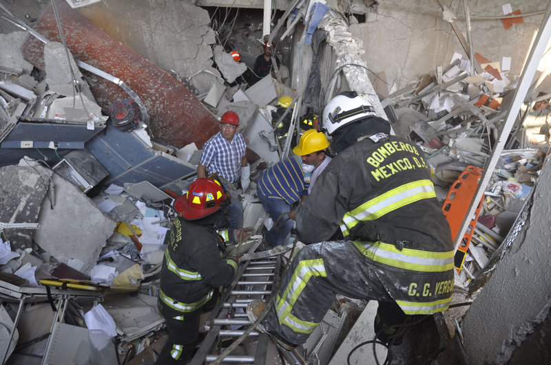 Firefighters and workers dig for survivors following an explosion at a building next to the 52-story tower of Petroleos Mexicanos, or Pemex, in Mexico City on Thursday.