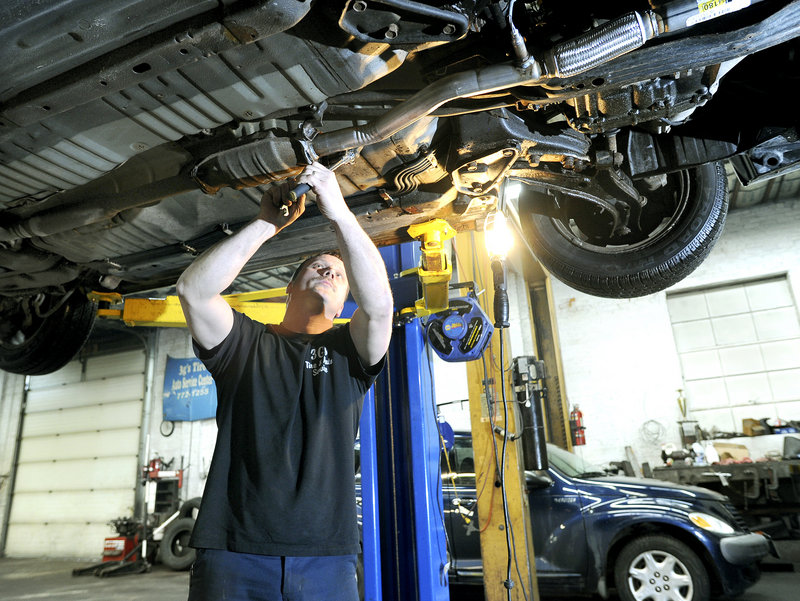 Auto technician Bob Burns installs a new exhaust system on a car at 3G’s Tire & Auto Service in Portland. Burns said manufacturers are getting better at sharing information, but it’s still difficult for mechanics to acquire scan codes for many ignition and security systems.