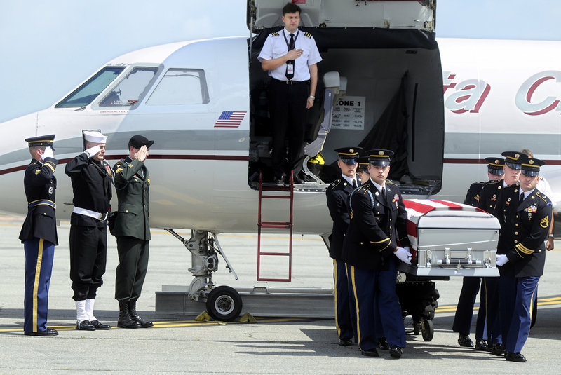 Service members salute as the remains of Staff Sgt. Eric Shaw arrive in July 2010 at Augusta State Airport, where they were escorted by the Maine Army National Guard’s Honor Guard.