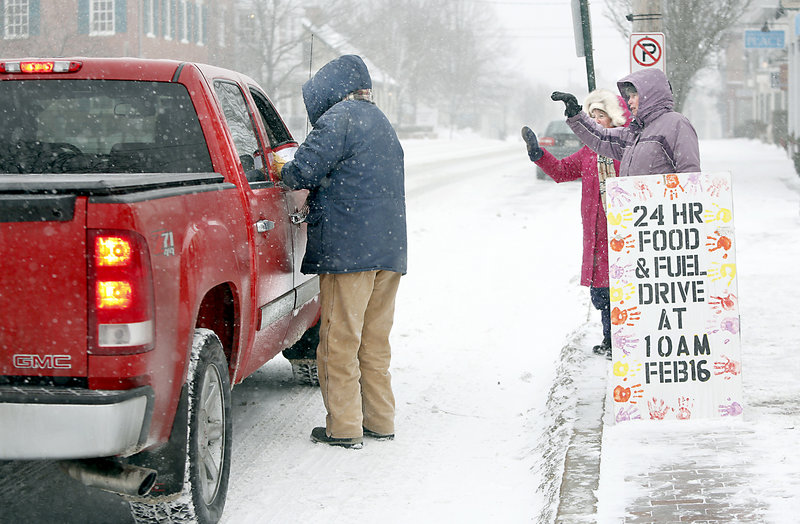 Sue Mack collects a donation from a passenger, as Patti Bruce, center, and Paula O’Brien wave Sunday in front of the First Parish Church on Main Street in Freeport.