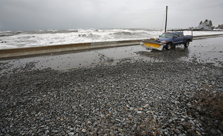 Stones tossed over a seawall by large waves cover Beach Avenue in Kennebunk on Friday.