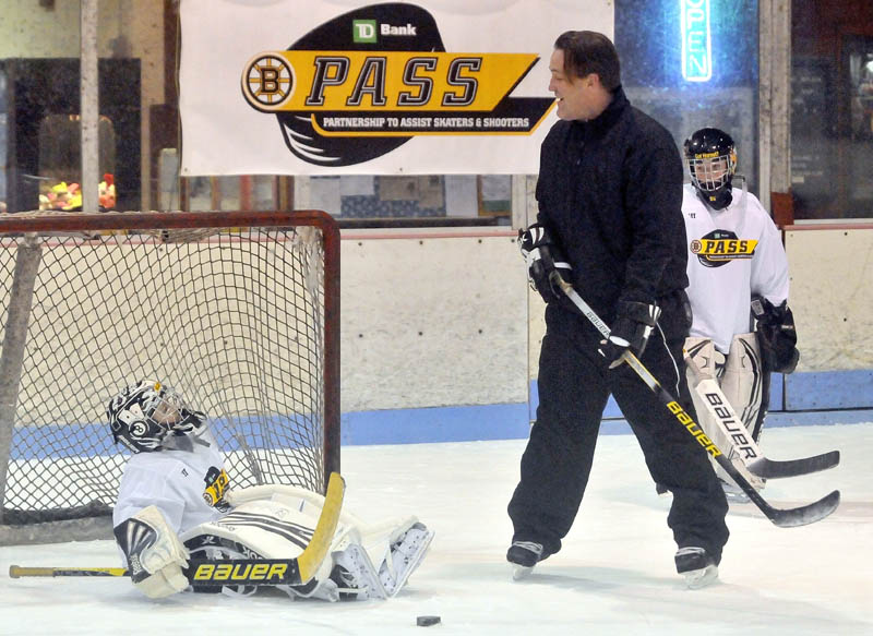 SEE WHAT I MEAN: Former Boston Bruin Bruce Shoebottom helps goalie Joshua Girard, 9, with his technique during a clinic Tuesday at Sukee Arena in Winslow. The Boston Bruins alumni association hosted the clinic with players from Central Maine Youth Hockey Association.