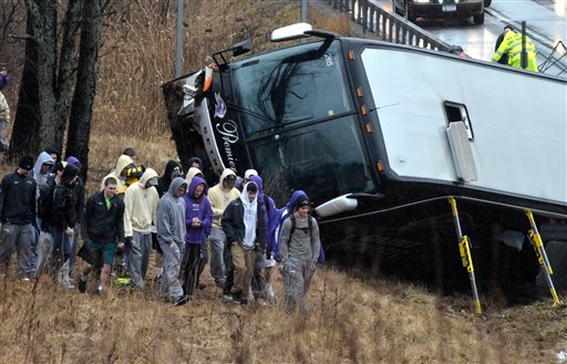 Members of the St. Michael's College lacrosse team walk away from the wrecked bus that was carrying them after it crashed on Tuesday.