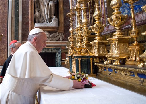 In this photo provided by the Vatican newspaper L'Osservatore Romano, Pope Francis puts flowers on the altar inside St. Mary Major Basilica in Rome on Thursday.