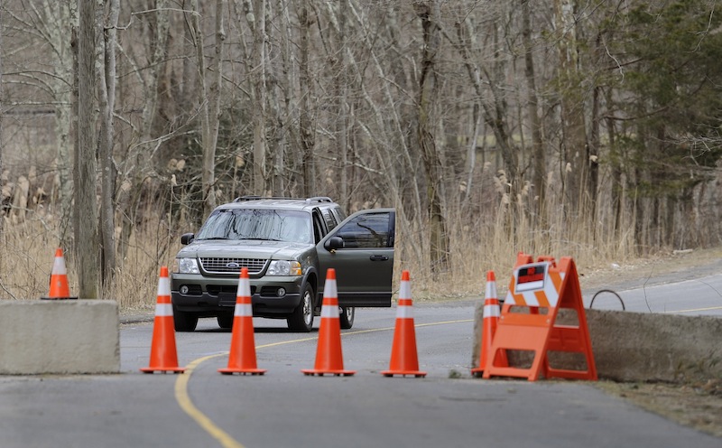 A guard stands watch behind cones and concrete barrier at the entrance to Sandy Hook Elementary School in Newtown, Conn., Thursday, March 28, 2013. Search warrants released Thursday, March 28, 2013, revealed that an arsenal of weapons including guns, more than a thousand rounds of ammunition, a bayonet and several swords was seized at Adam Lanza's home. Lanza killed his mother, Nancy Lanza in their home before he forced his way into Sandy Hook Elementary School in Newtown, Conn, killing 26 people. (AP Photo/Jessica Hill)