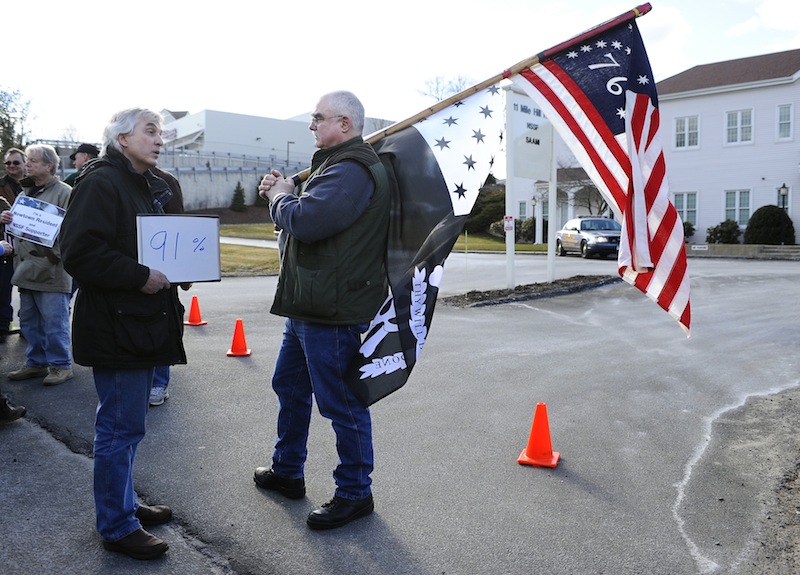 John Woodall. left, of Newtown, Conn., carries a sign that he says indicated the percentage of Americans who support universal background checks speaks with Gordon Jones of Southbury, Conn., a supporter of gun rights during a rally outside the National Shooting Sports Foundation headquarters in Newtown Thursday, March 28, 2013. Search warrants released Thursday, March 28, 2013, revealed that an arsenal of weapons including guns, more than a thousand rounds of ammunition, a bayonet and several swords was seized at Adam Lanza's home. Lanza killed his mother, Nancy Lanza in their home before he forced his way into Sandy Hook Elementary School in Newtown, Conn, killing 26 people. (AP Photo/Jessica Hill)