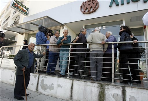 People wait outside a Coop bank branch in Nicosia, Cyprus, on Thursday. Bank branches across the country were being replenished with cash, and were scheduled to open for six hours at noon.