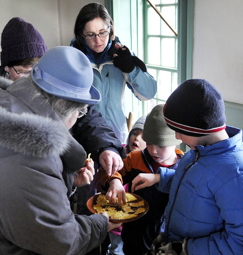 Old Fort Western guests sample cornbread cooked in a fireplace at the historic landmark, on the banks of the Kennebec River, on Sunday in Augusta, during Maple Syrup Sunday festivities. Visitors learned about tapping maple trees with sumac, evaporating sap in kettles and the food consumed by early settlers of the Kennebec valley.