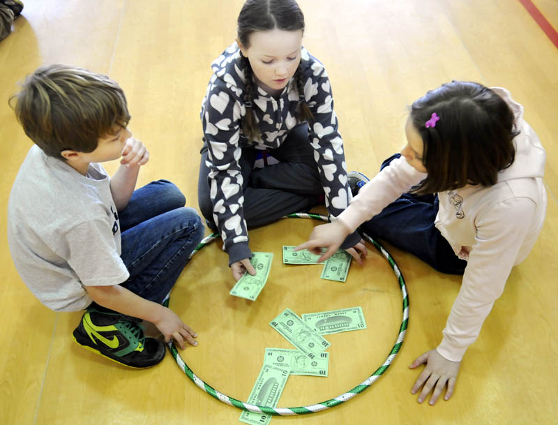 Whitefield Elementary School Sullivan Anderson, Miranda Northrup, center, and Abby Peaslee count money they collected Tuesday during physical education class.