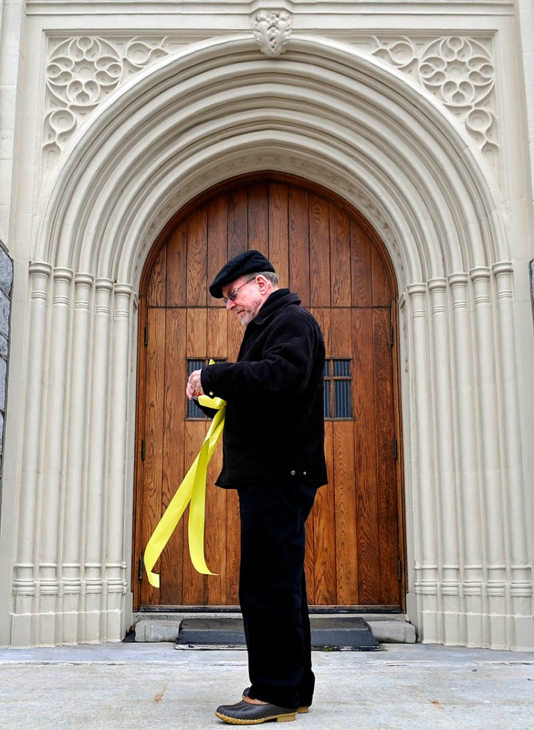 Rev. Francis Morin hangs a ribbon on the entrance of St. Mary's Catholic Church in Augusta Wednesday, moments after the announcement of a new pope. Jorge Bergoglio, 76, of Argentina, was elected pope and chose the name Francis, becoming the first pontiff from the Americas and the first from outside Europe in more than a millennium.