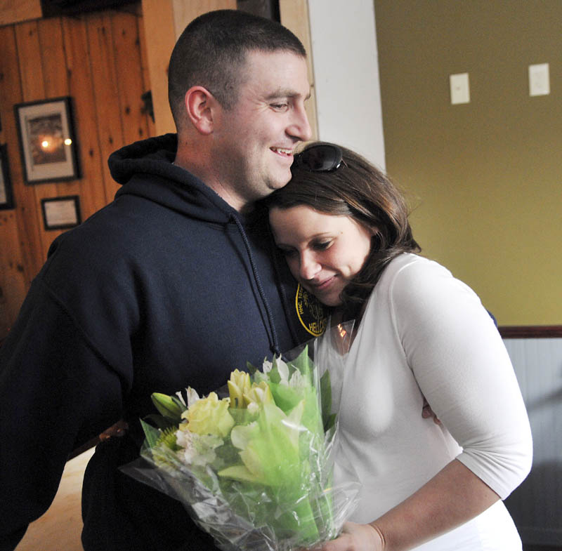 Megan McGuire hugs her husband, Travis, on Wednesday, moments after he surprised her by returning early from an Army deployment in Afghanistan, to be present for the birth of their first child. Travis McGuire walked into the Depot Sports Bar in Gardiner and gave his wife a bouquet of flowers as she dined with family and friends.