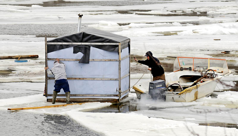 Jimmy Worthing, left, and a member of his smelt camp crew retrieve a shack floating on a sheet of ice Tuesday in the Kennebec River in Randolph after several shacks drifted away from Worthing's Smelt Camps. Worthing and a crew broke ice with a boat and towed several stray shacks back to shore.