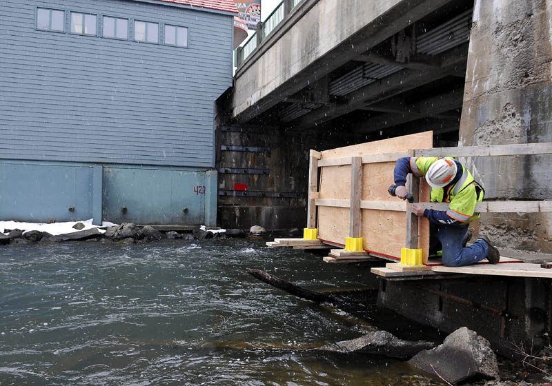 Maine Department of Transportation worker Keith Bates erects a railing on a platform, attached to a pier suspending the bridge spanning Cobbossee Stream, on Bridge Street in Gardiner Monday. Crews will be replacing concrete in the pier for the next four to six weeks, according to bridge maintenance supervisor George James.